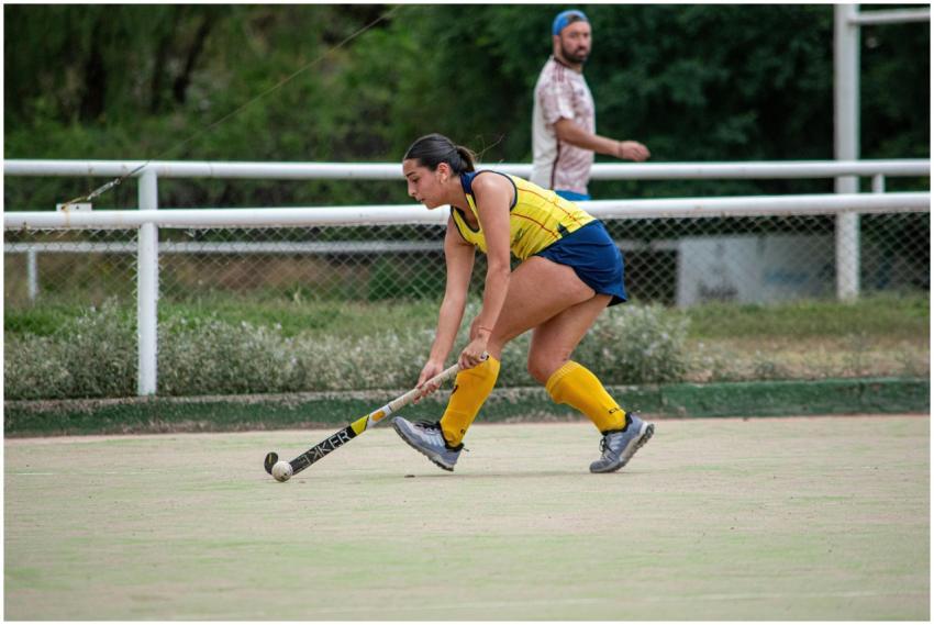 Dynamic field hockey scene with female player hitt