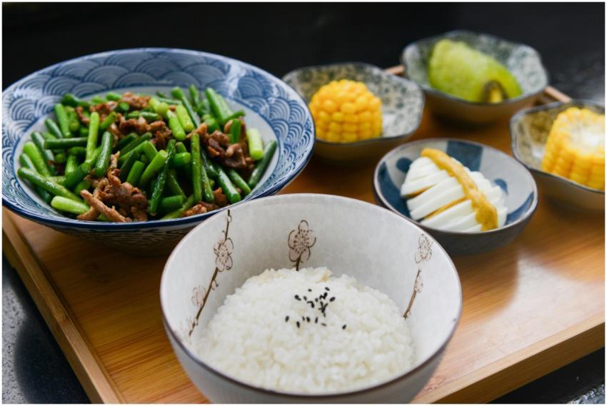A vibrant Asian meal featuring rice, green beans,