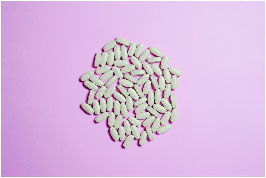A cluster of white pills on a purple surface, high