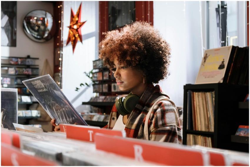 A woman with afro hair examines vinyl records in a