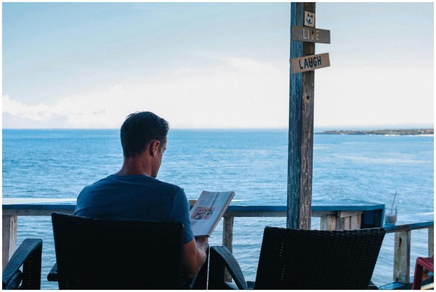 A man relaxes with a book overlooking the ocean in