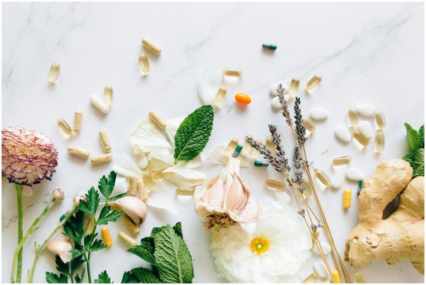 A flatlay of natural herbs, supplements, and flowe