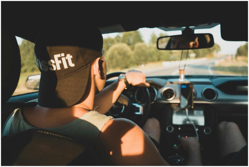 View of a young man driving a car on a rural road,