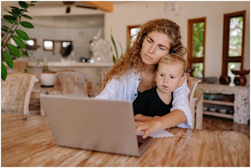Mother and child using a laptop at home, working a