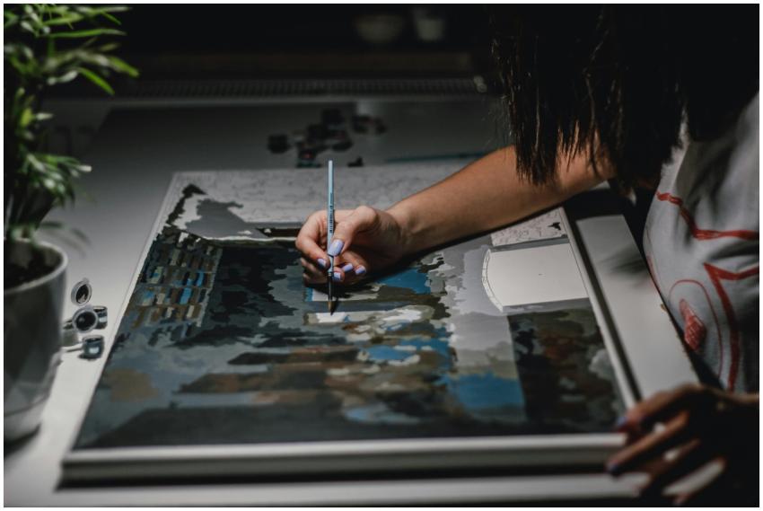 A close-up view of a person painting on a canvas,