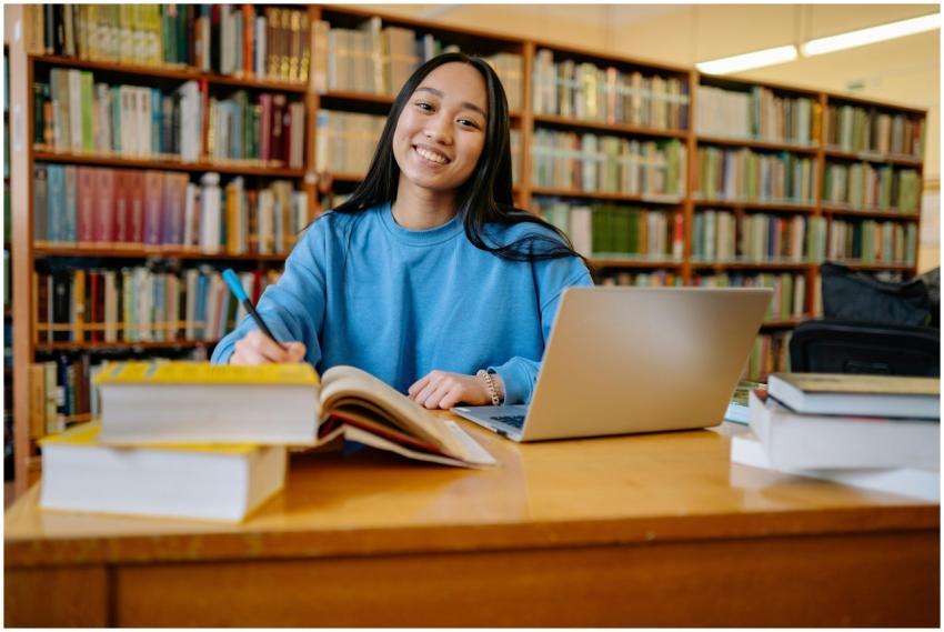 Smiling student studying in a library with books a