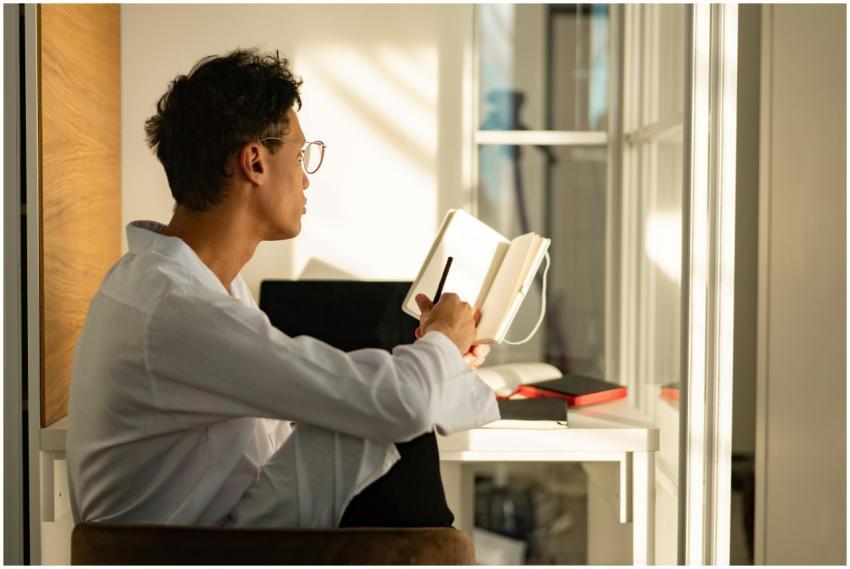 A young man sitting by a window in a sunlit home o