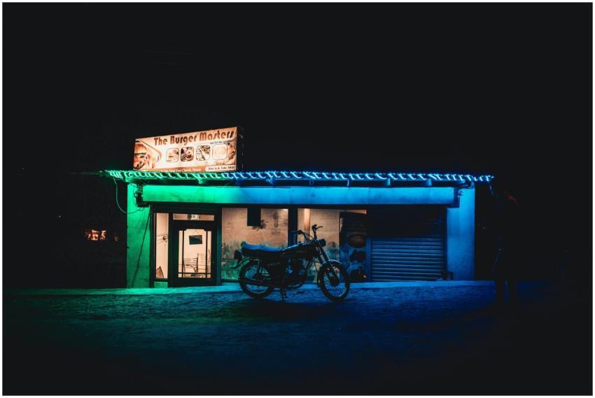 A motorcycle parked outside a neon-lit burger shop