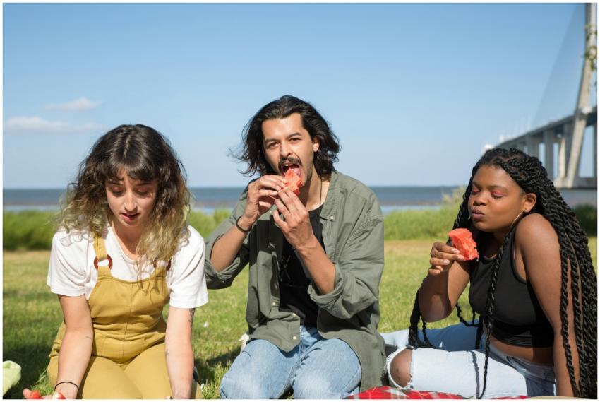 Three friends having a picnic with watermelon near