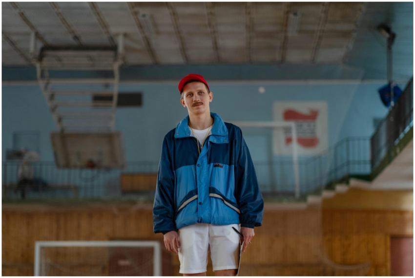 Male sports coach in blue jacket standing indoors