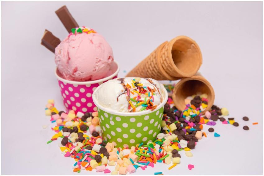 Delicious ice cream in vibrant cups with scattered