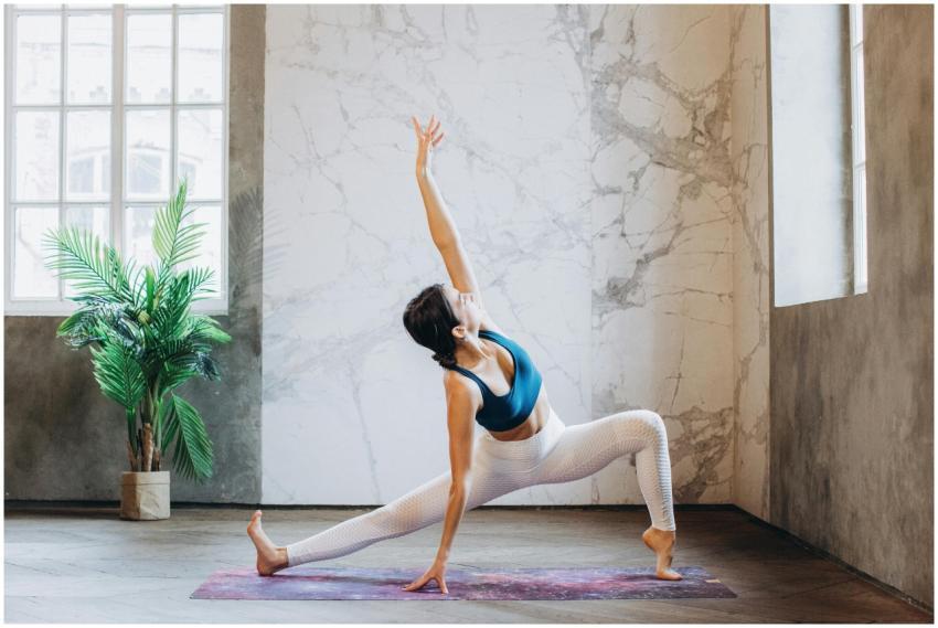 Flexible woman performs a yoga pose in a sunlit an