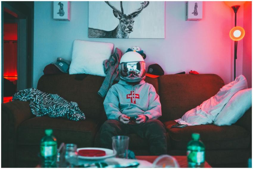 A person wearing a VR helmet, gaming on a couch in