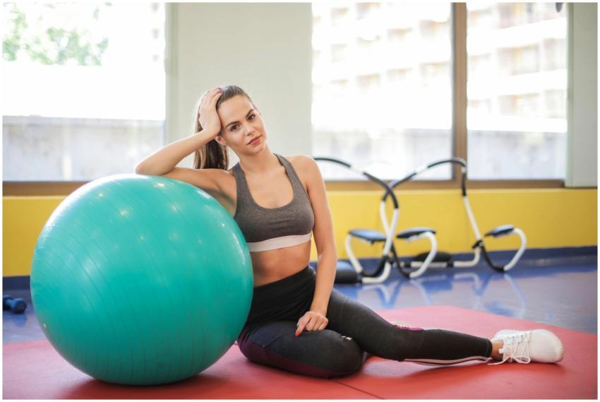 A woman in fitness attire sitting on a mat, leanin