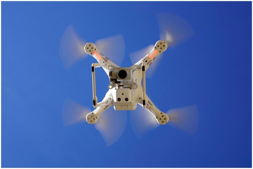 Aerial view of white drone flying with rotating bl