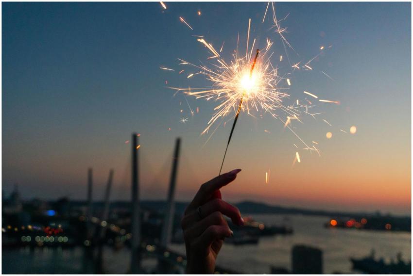 Hand holding sparkler at sunset with a view of Vla