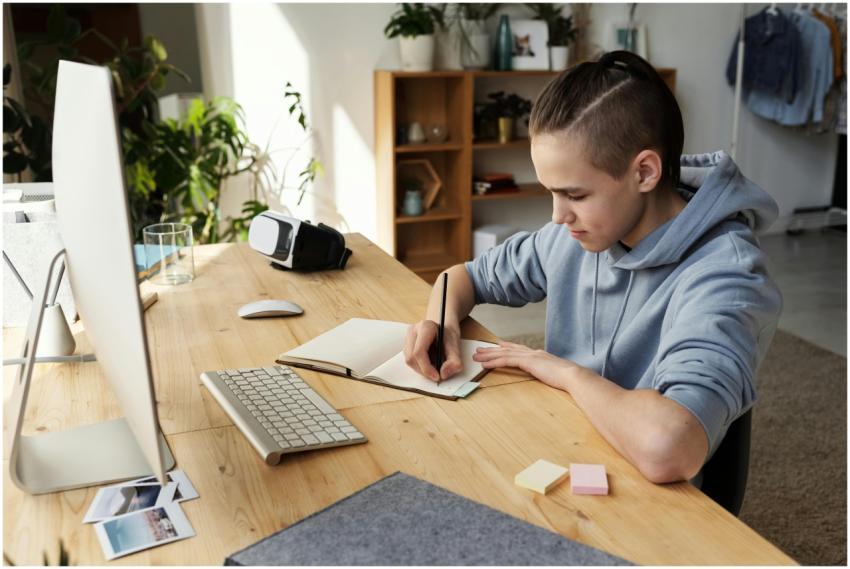 A teenage boy focuses on his studies at home, writ