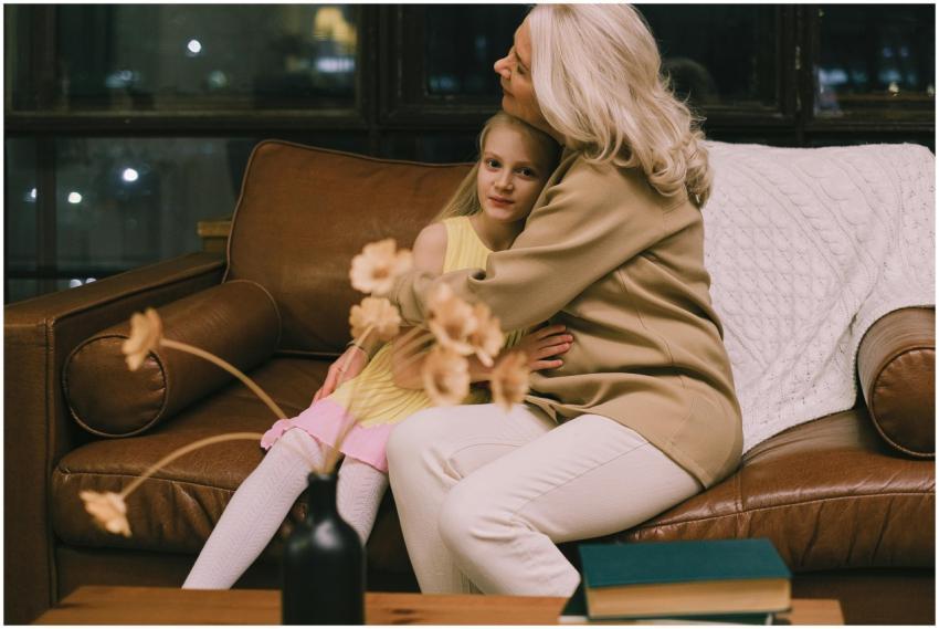 Grandmother and granddaughter hugging on a sofa, s