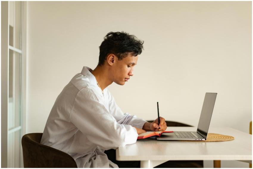 Young man in casual attire writing notes while stu