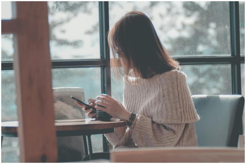 A woman relaxing indoors with coffee, texting on h