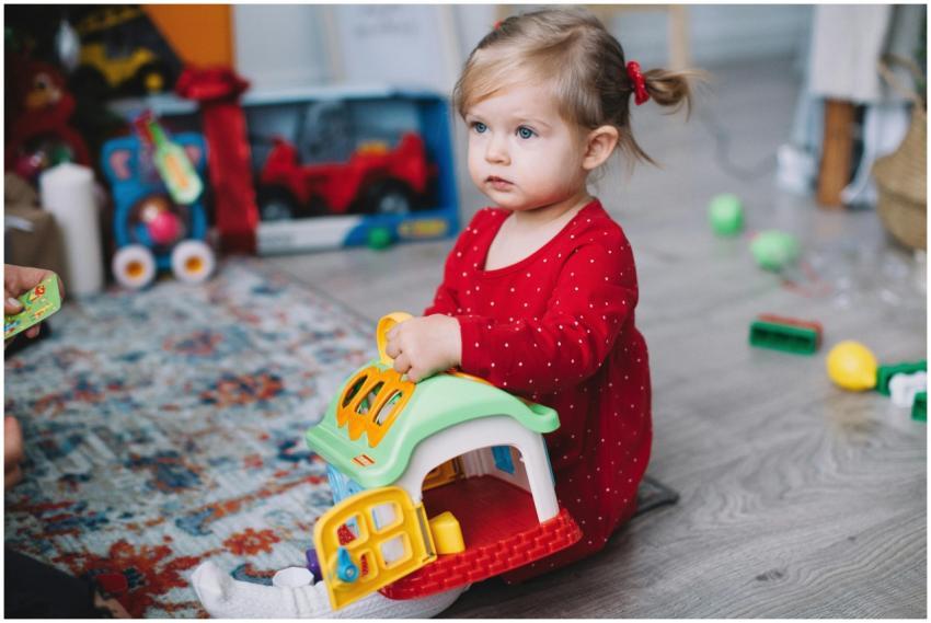 Adorable toddler in red outfit playing with toy ho