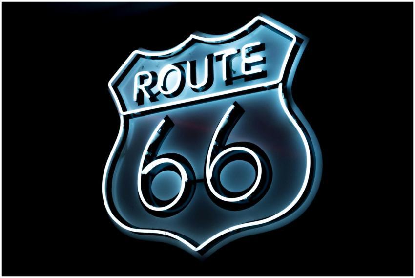 Bright neon Route 66 sign glowing on a black backg