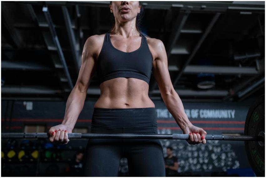 Strong woman lifting barbell in gym. Focus on fitn