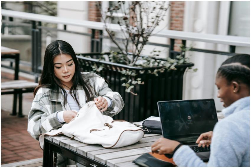 Young multiethnic female students sitting at woode