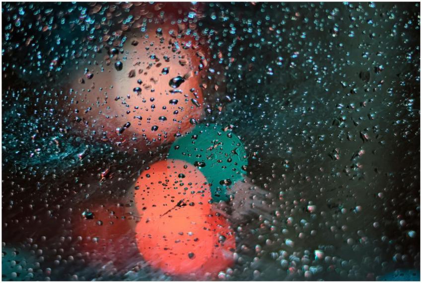 Close-up of raindrops on a window with blurred cit