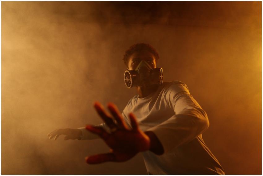 A man in a gas mask reaches out through a smoky, b