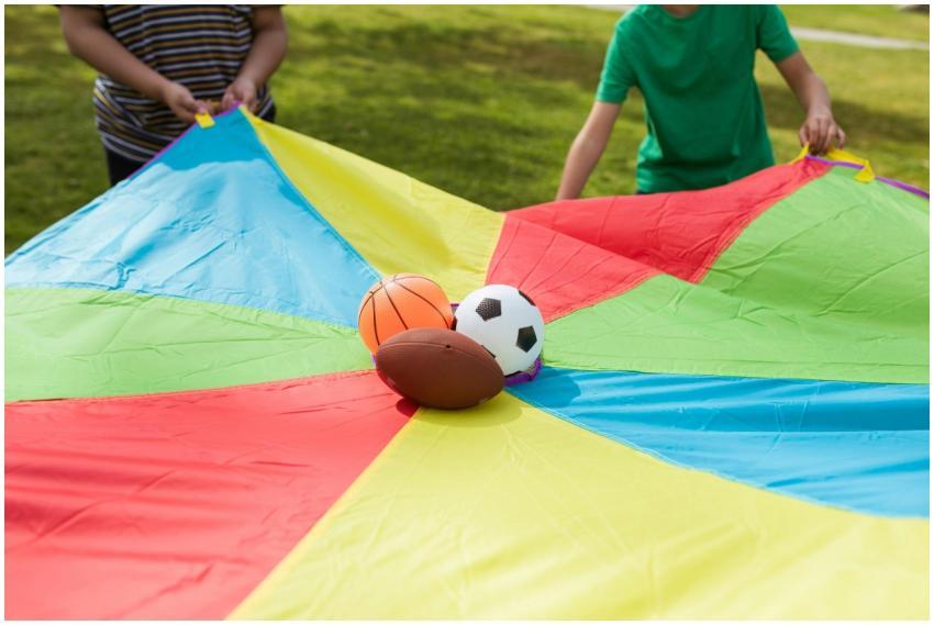 Children playing outside with a colorful parachute