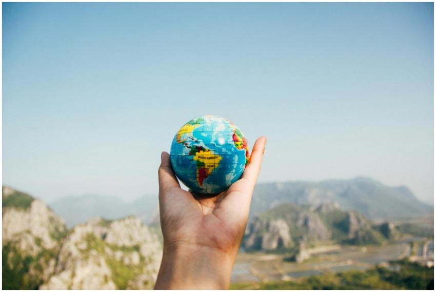 Hand holding a globe against a mountain background