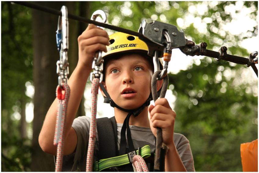 A young boy enjoying a rope climbing activity outd