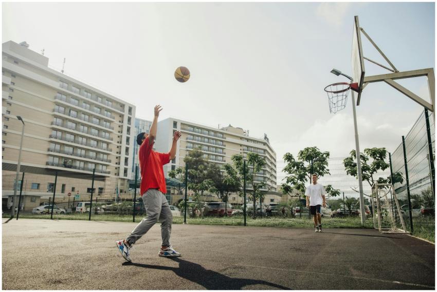 Two men playing basketball on an outdoor court in
