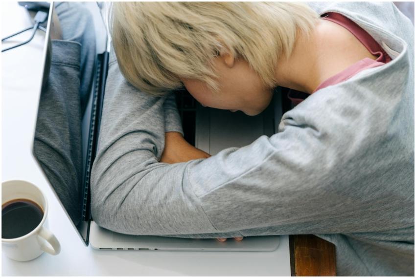 Tired woman resting her head on a laptop, symboliz