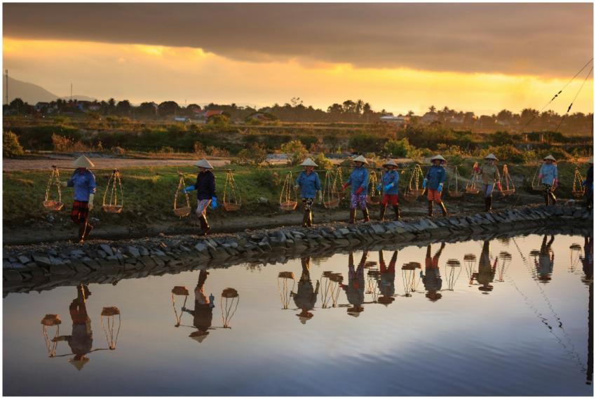 A group of Asian farmers carrying baskets reflecti