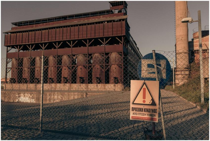 Rusty industrial building with warning sign and fe