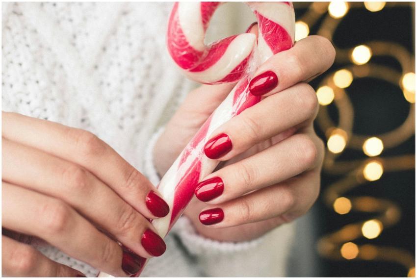 Close-up of hands with red nails holding a candy c