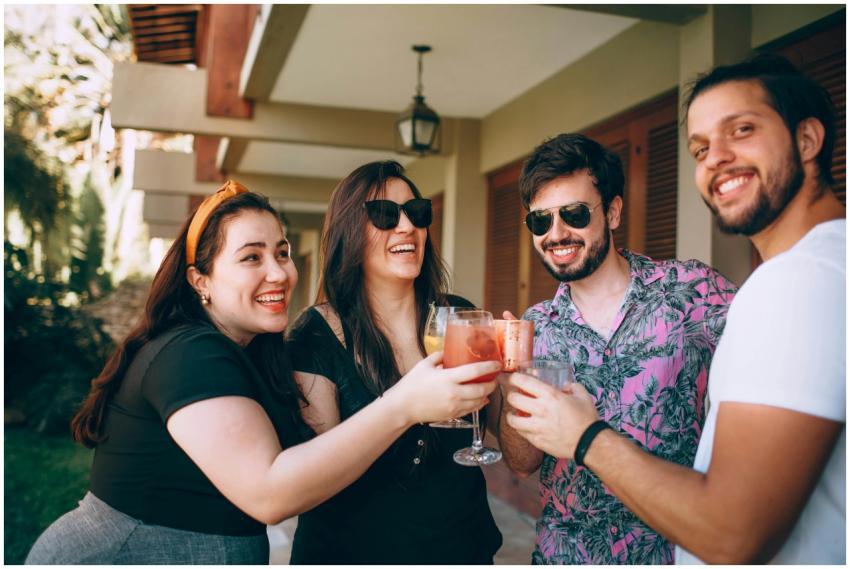 Group of friends smiling and toasting drinks outsi