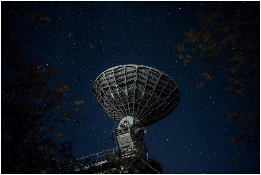 A large radio telescope beneath a starry night sky
