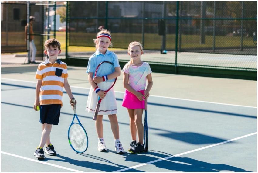 Group of kids playing tennis outdoors, showcasing