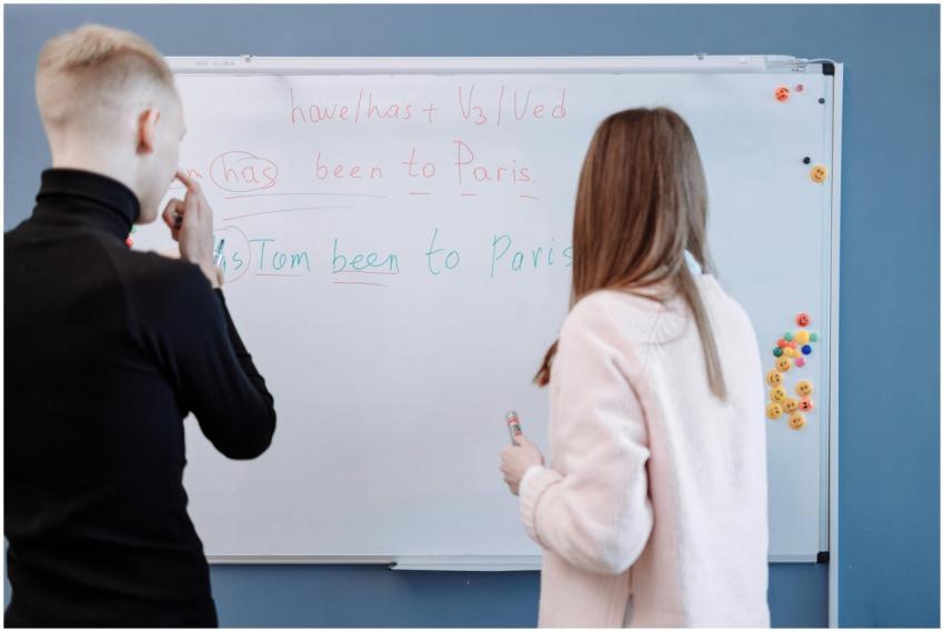 Two students studying English grammar at a whitebo