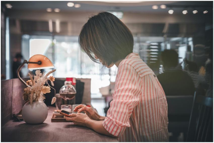 A woman in a café using a smartphone, surrounded b