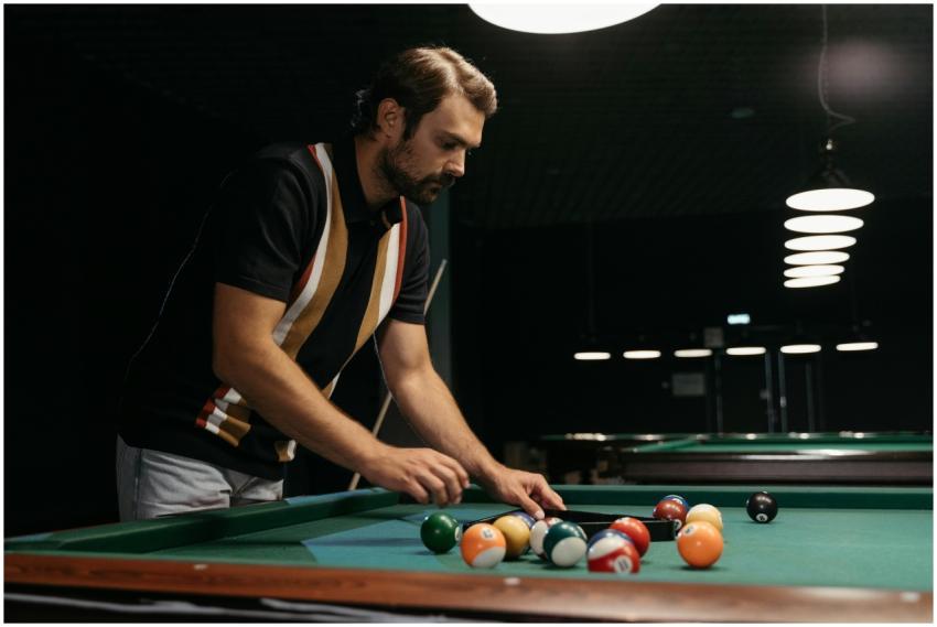 Man arranging billiard balls on a pool table, focu