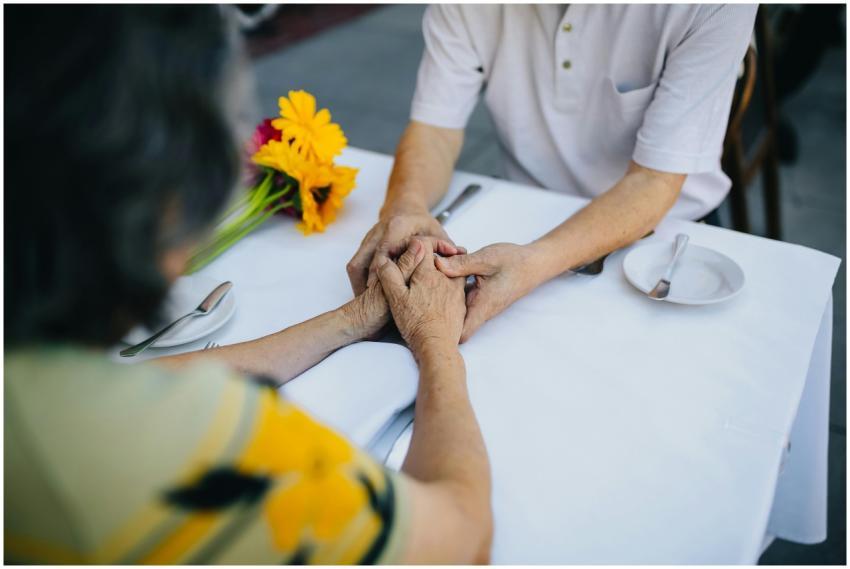 Elderly couple holding hands on a cafe table outdo