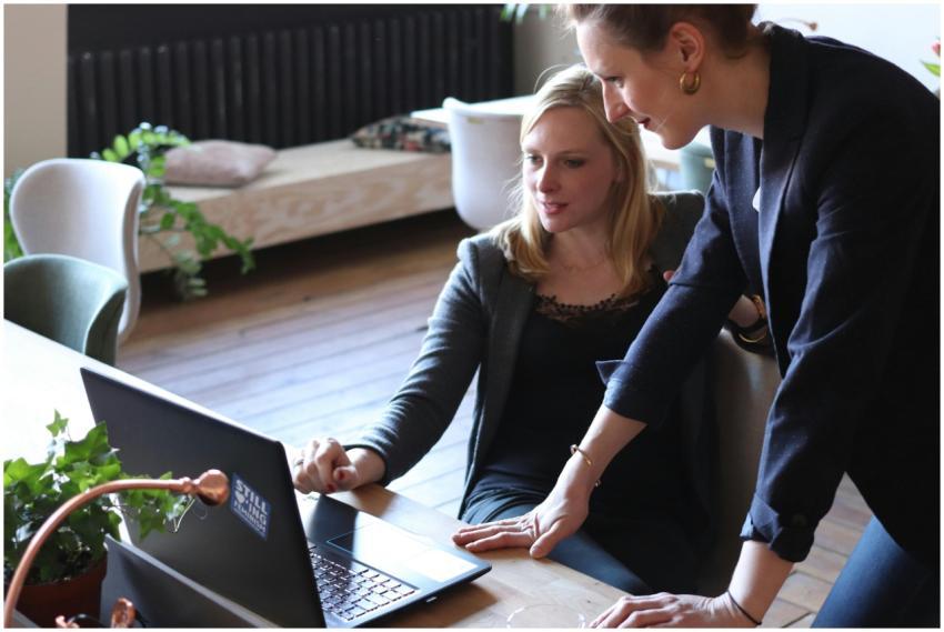 Two professional women discuss a project using a l