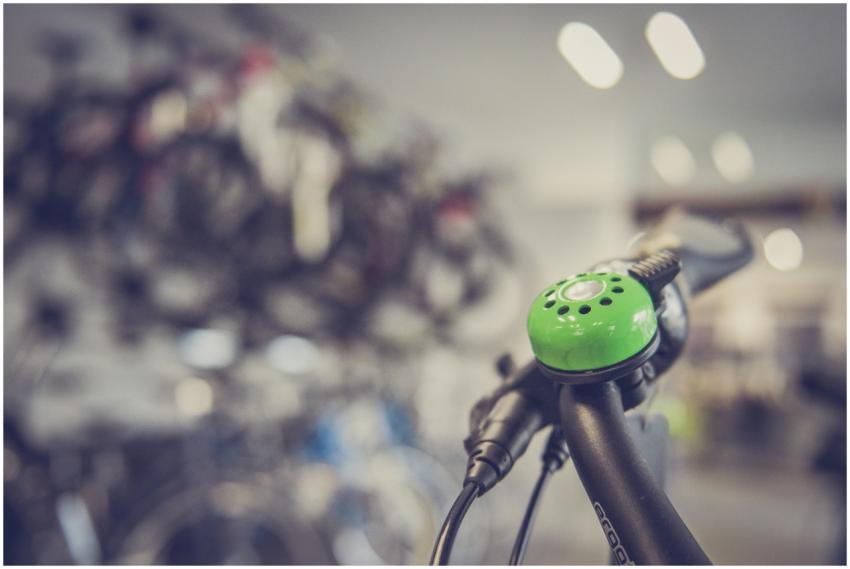 Close-up of a green bicycle bell on handlebars wit