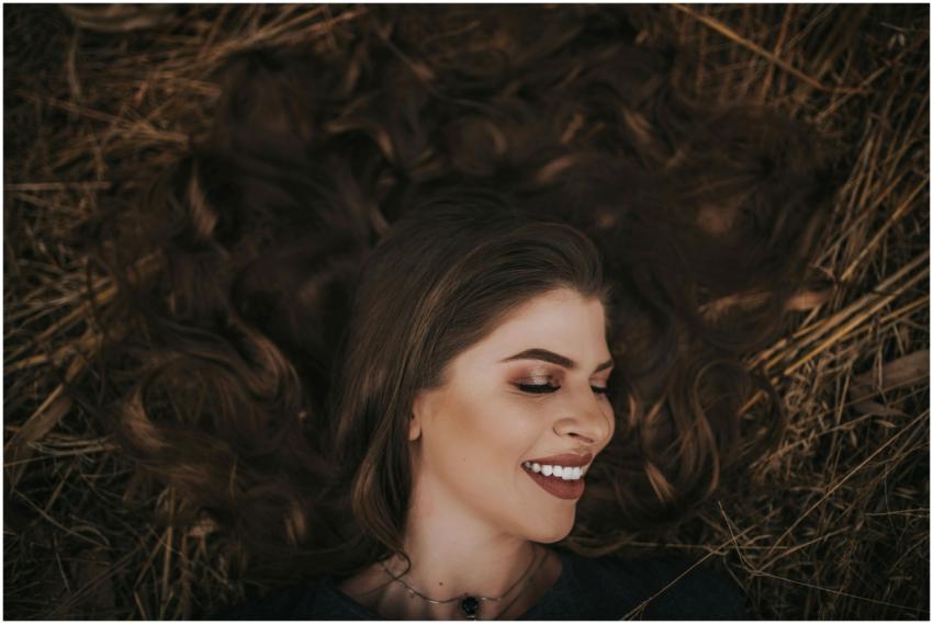 A woman with eyes closed and smiling, lying on aut