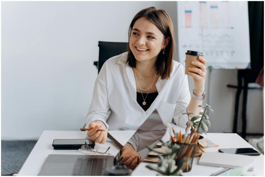 Smiling woman holding coffee cup at modern office