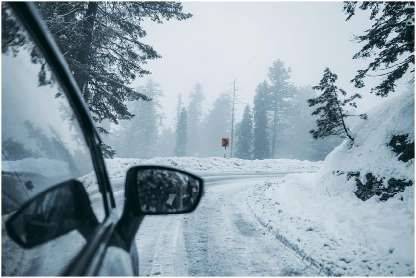 A car drives through a foggy snow-covered mountain